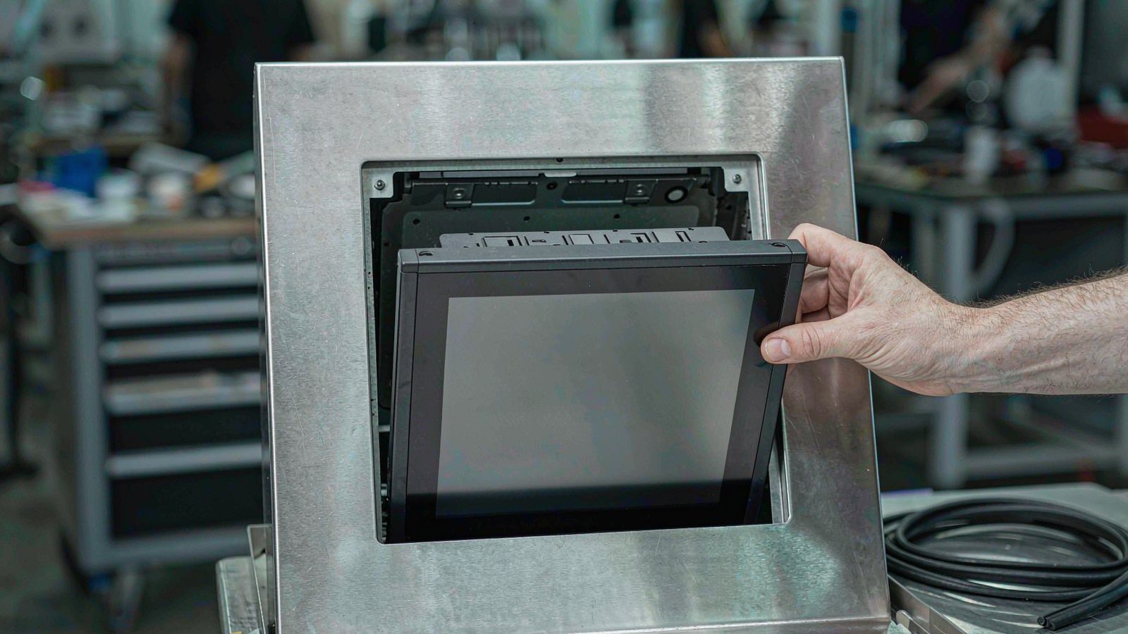 Technician panel-mounting an industrial panel PC into a cut steel cabinet door