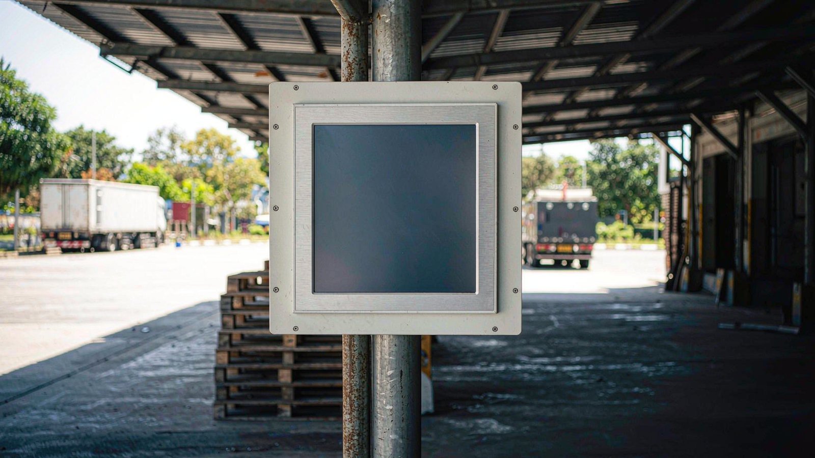 Industrial panel PC mounted under a canopy at a tropical loading dock in bright daylight